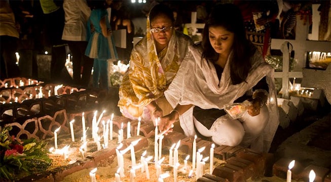 two women sitting on ground lighting candles