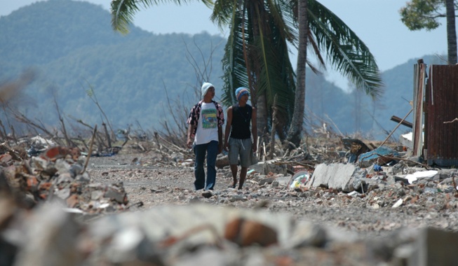 two men walking through rubble after natural disaster