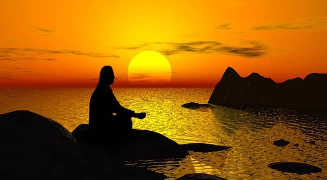 silhouette of a person meditating with sunset in the background